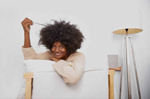 Smiling woman wit natural hair pulling a lock into the air